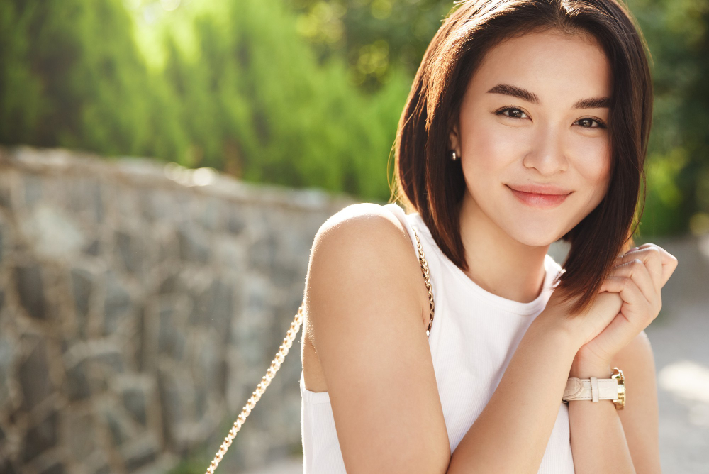 Close-up attractive asian woman smiling at camera, walking in park